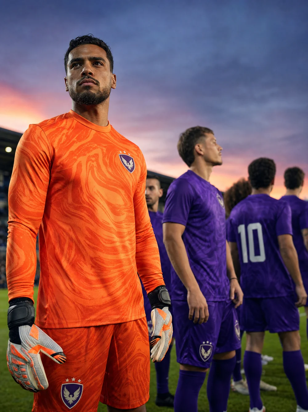 Time de futebol com o goleiro em camisa de cor contrastante laranja em primeiro plano